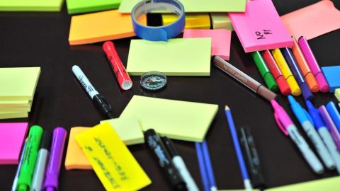 Colorful assortment of office supplies on a desk, including sticky notes, pens, and markers.